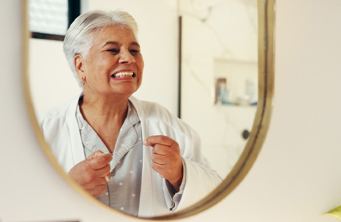 Woman flossing in front of a mirror