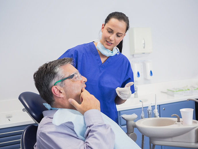 Man in dental chair pointing to his tooth while talking to his dentist in Bethlehem