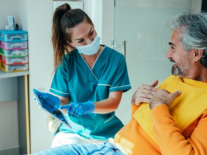 Dental team member showing a tablet screen to a patient