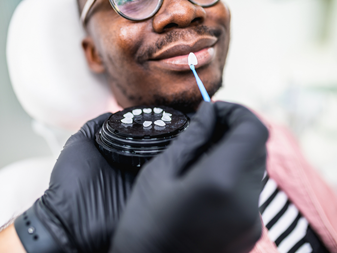 Bethlehem cosmetic dentist holding a veneer in front of a patients smile