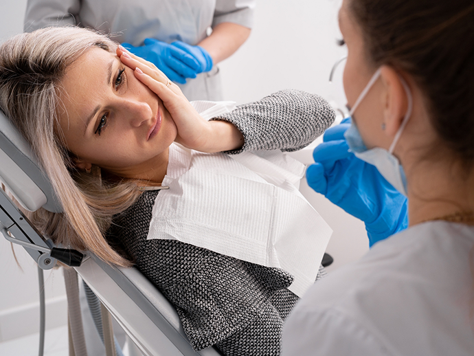 Woman holding her cheek in pain while talking to her emergency dentist in Bethlehem