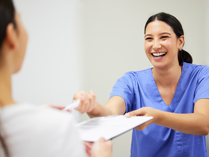 Dental team member handing a clipboard to a patient