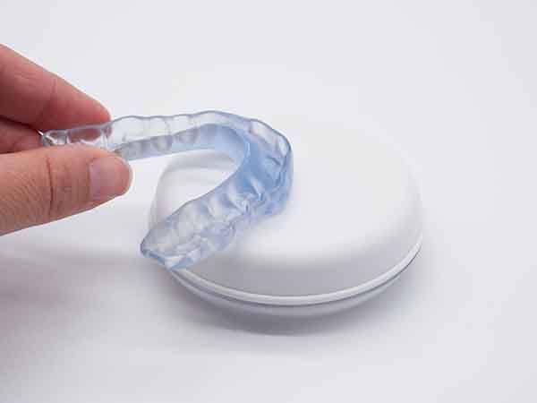 A hand holding a transparent mouthguard