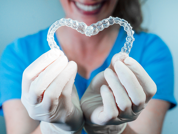 Dentist making a heart shape out of two Invisalign clear aligners in Bethlehem