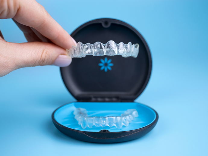 Hand placing an Invisalign aligner into its storage case