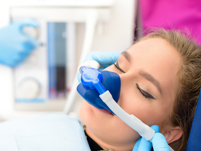 Woman in dental chair wearing a nitrous oxide mask over her nose